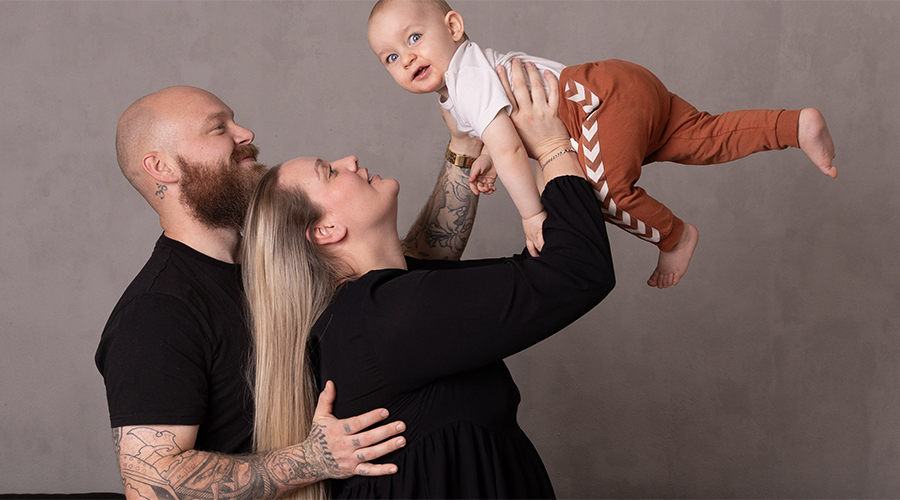 Billede af familie - Barnet holdes højt i luften.